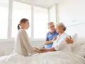 Rodzina wspiera starszą panią w łóżku. Pokazuje, jak postępować z osobą chorą psychicznie: z miłością i troską.