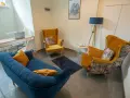 Nowoczesny gabinet psychologiczny z żółtymi fotelami, niebieską kanapą i biurkiem.