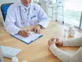 Lekarz notuje na karcie pacjenta, omawiając, ile wynosi renta dla chorych psychicznie.
