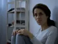 Zmartwiona kobieta siedzi przy ścianie. Jak zmusić schizofrenika do leczenia? Potrzebna jest empatia i wsparcie.