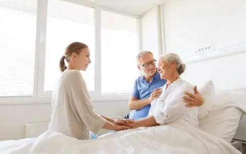 Rodzina wspiera starszą panią w łóżku. Pokazuje, jak postępować z osobą chorą psychicznie: z miłością i troską.