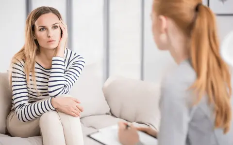 Kobieta na kanapie, zamyślona, podczas sesji, która pokazuje, czym jest psychoterapia.