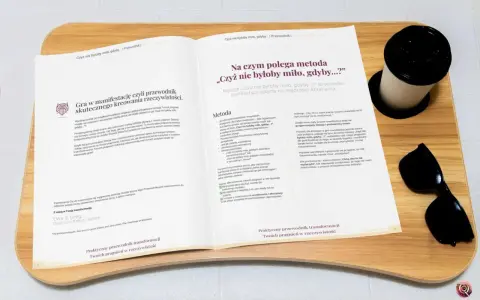 Otwarta książka z tekstem o manifestacji, obok kubek i okulary przeciwsłoneczne.