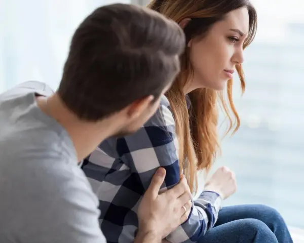 Mężczyzna pociesza kobietę, która zmaga się z trudnościami. Czy zaburzenia adaptacyjne to choroba psychiczna?