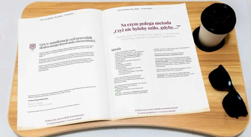 Otwarta książka z tekstem o manifestacji, obok kubek i okulary przeciwsłoneczne.
