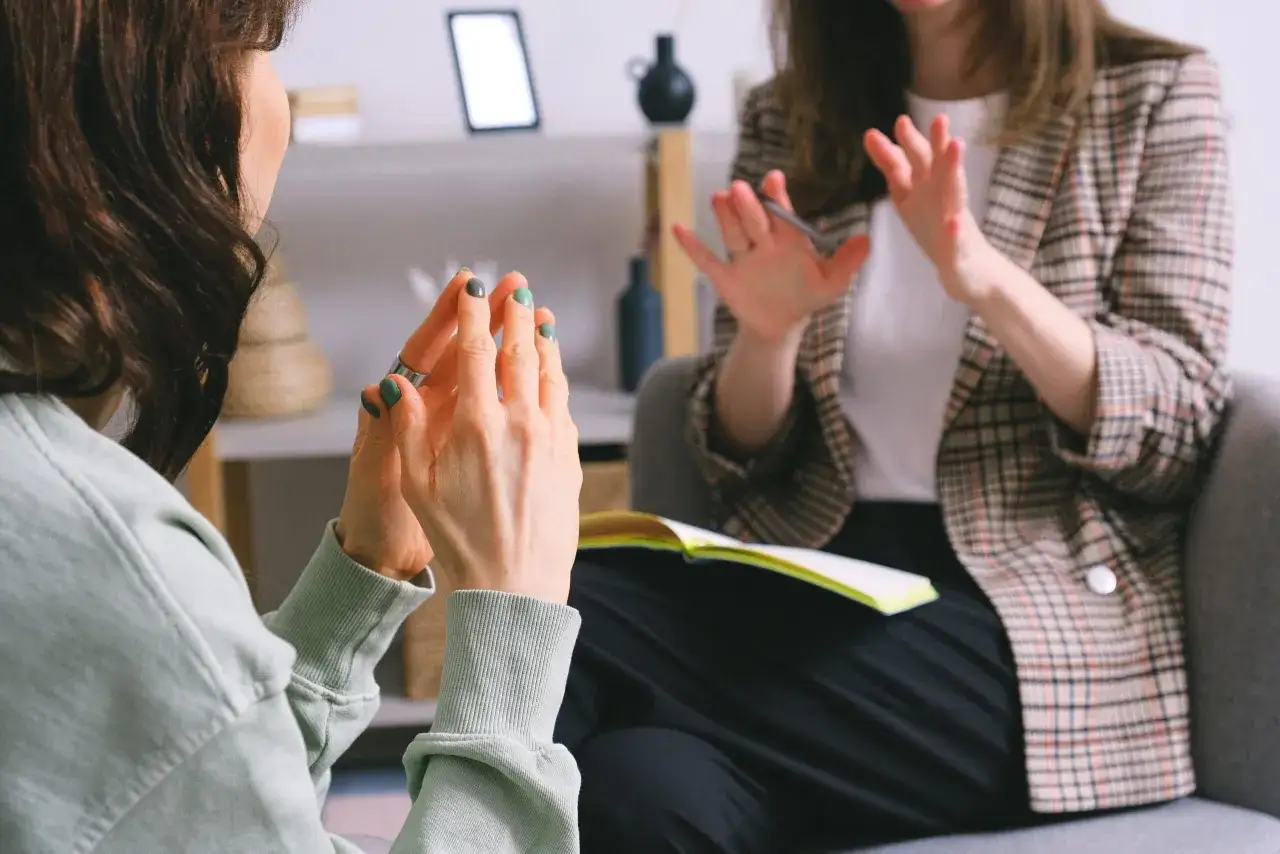 Dwie kobiety rozmawiają, jedna z nich gestykuluje, co może być częścią rozmowy o tym, jak postępować z osobą chorą psychicznie.