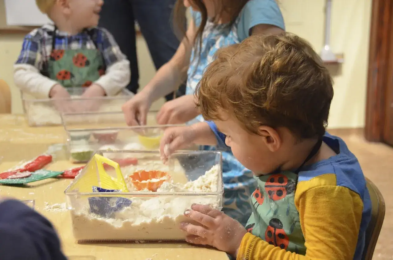 Dzieci bawią się piaskiem kinetycznym, co może być częścią terapii na zaburzenia sensoryczne.